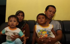 PASRAH: Davin Evan Bachtiar bocah yang diduga korban malpraktek duduk di pangkuan ayahnya bersama ibu dan adiknya.